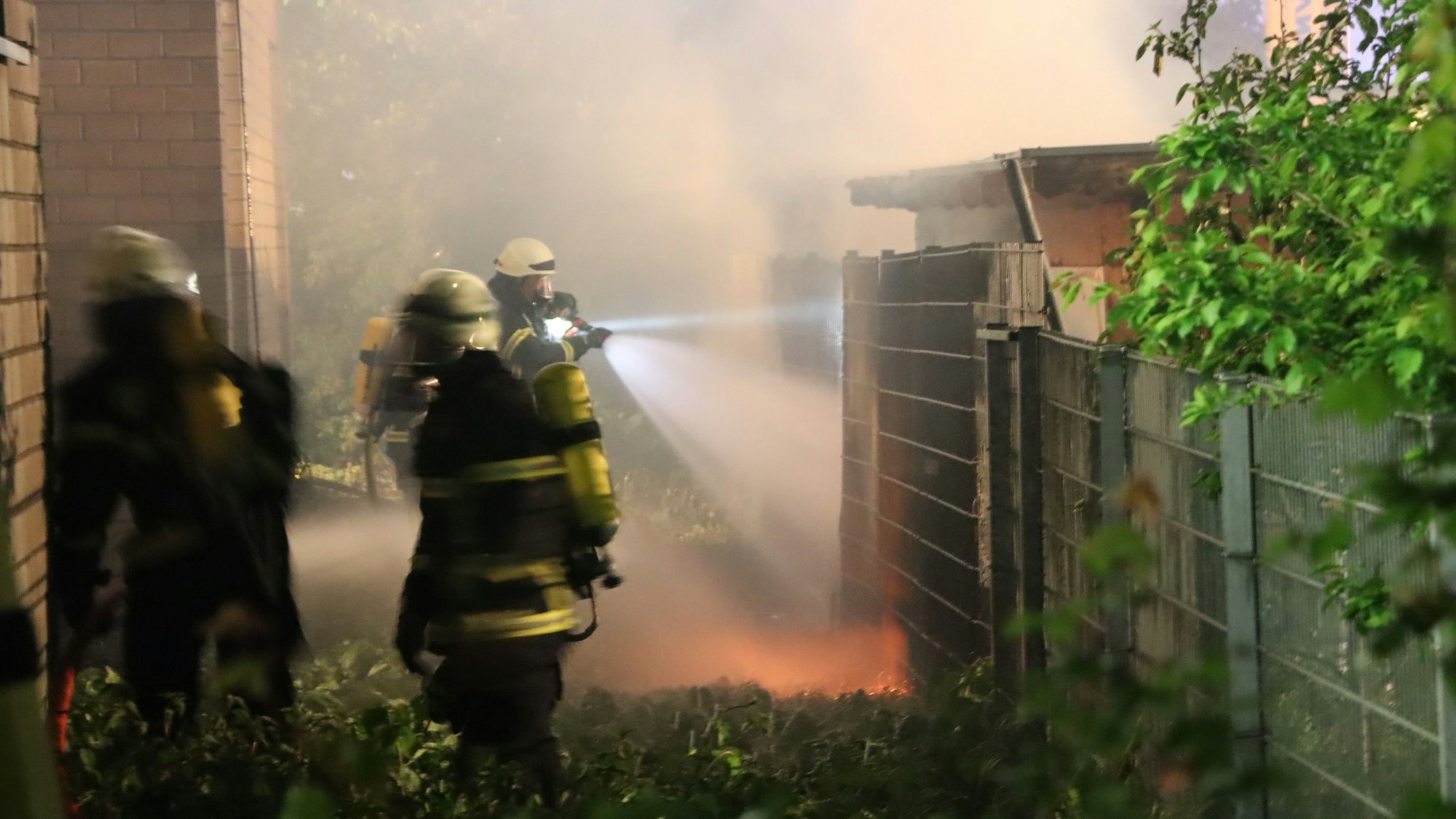 Man sieht Menschen in Feuerwehrkleidung, die einen Brand löschen.