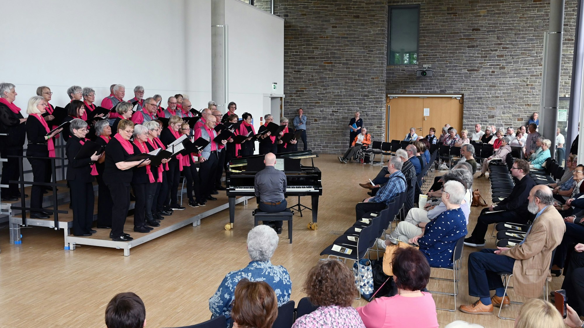 Zu sehen ist der Auftritt eines Chores aus Männern und Frauen.