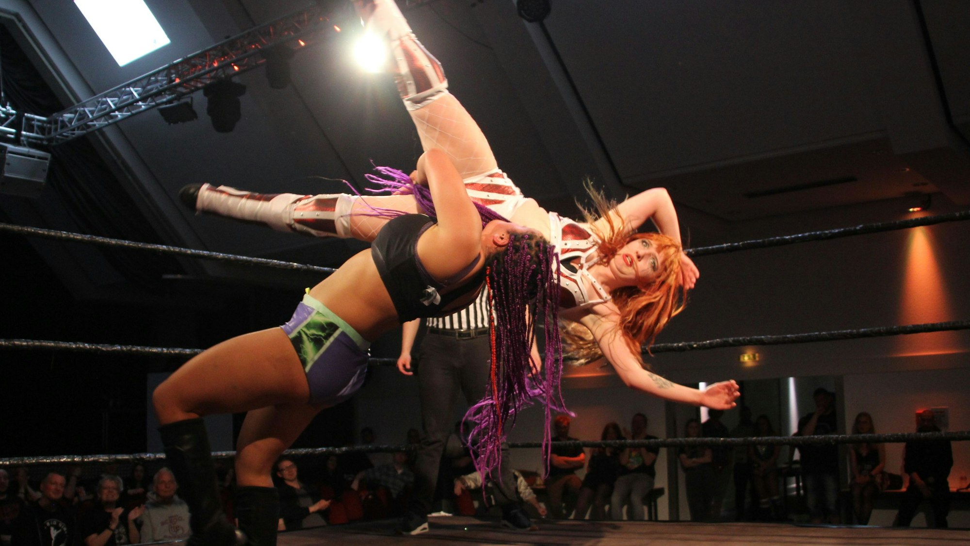 Eine Wrestlerin wirft ihre Gegnerin spektakulär über die Schulter auf den Boden des Rings.