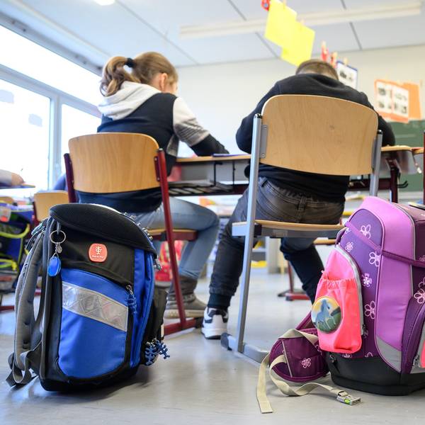 Kinder sitzen mit ihren Ranzen in einer Klasse.
