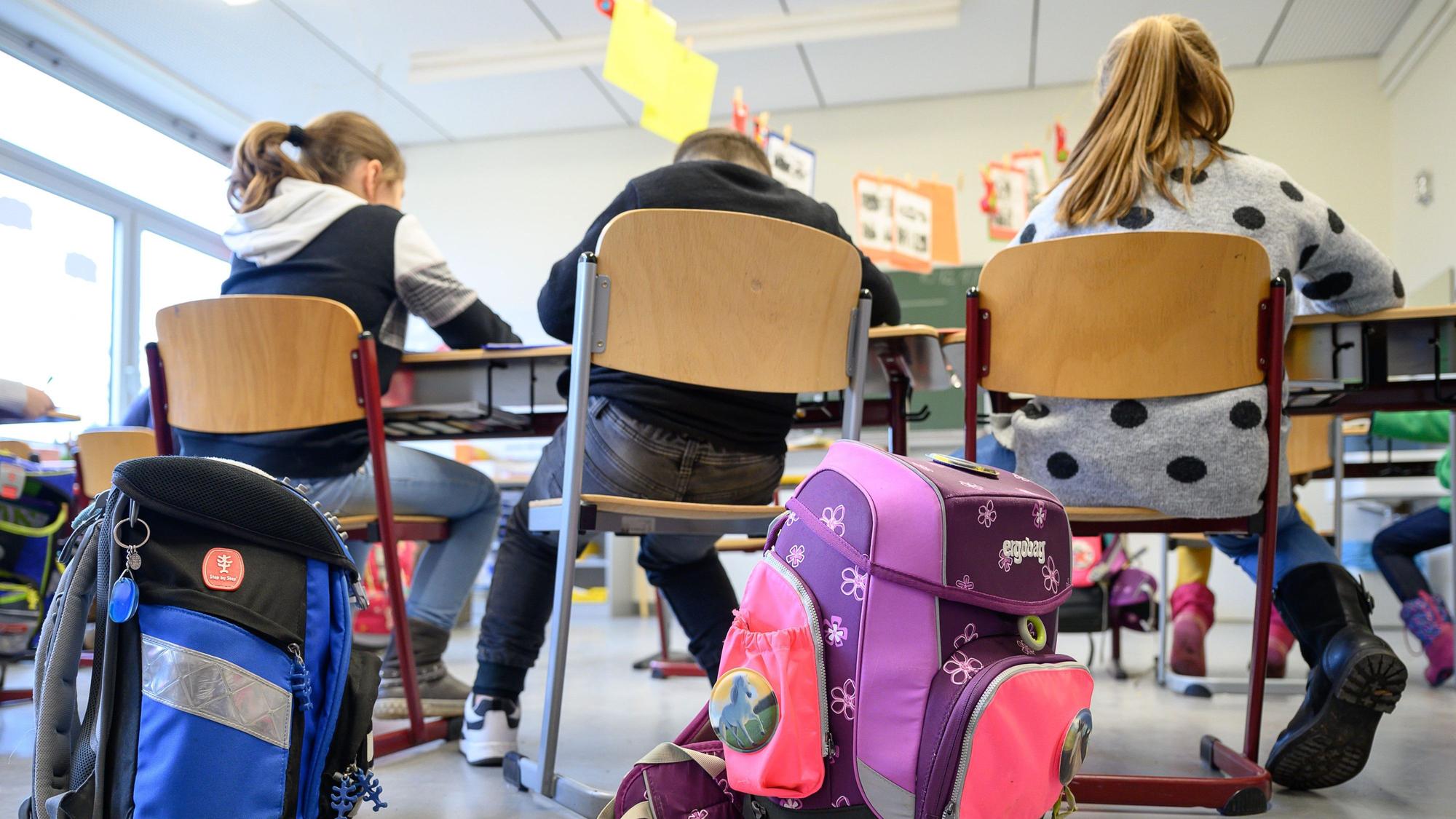 Kinder und Ranzen von hinten in einer Grundschulklasse