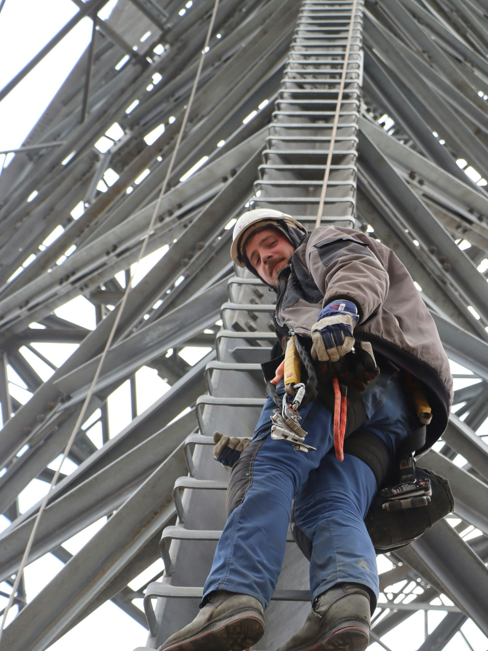 Das Bild zeigt Flamur Kovrigin, der auf den Stufen eines Hochspannungsmastes steht.