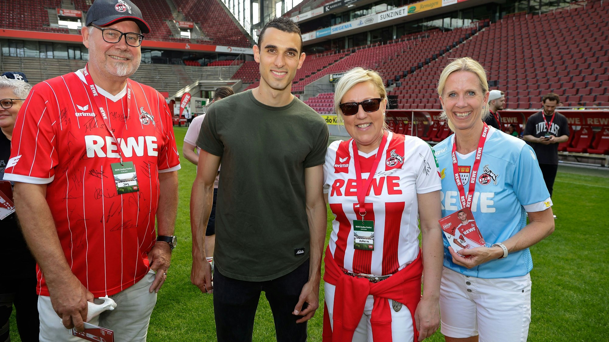 Menschen im Trikot vom 1. FC Köln stehen nebeneinander.