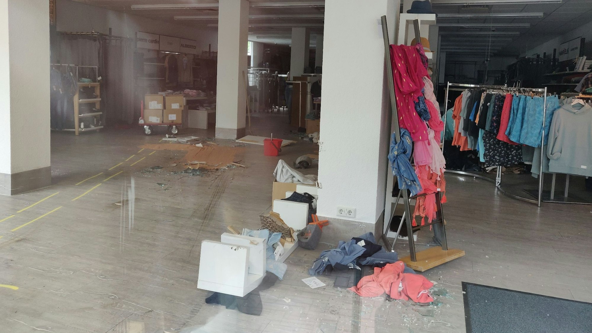 Blick ins geschlossene Herrenmodegeschäft, gelbe Markierungen zeigen die Spur der Irrfahrt des Wagens.