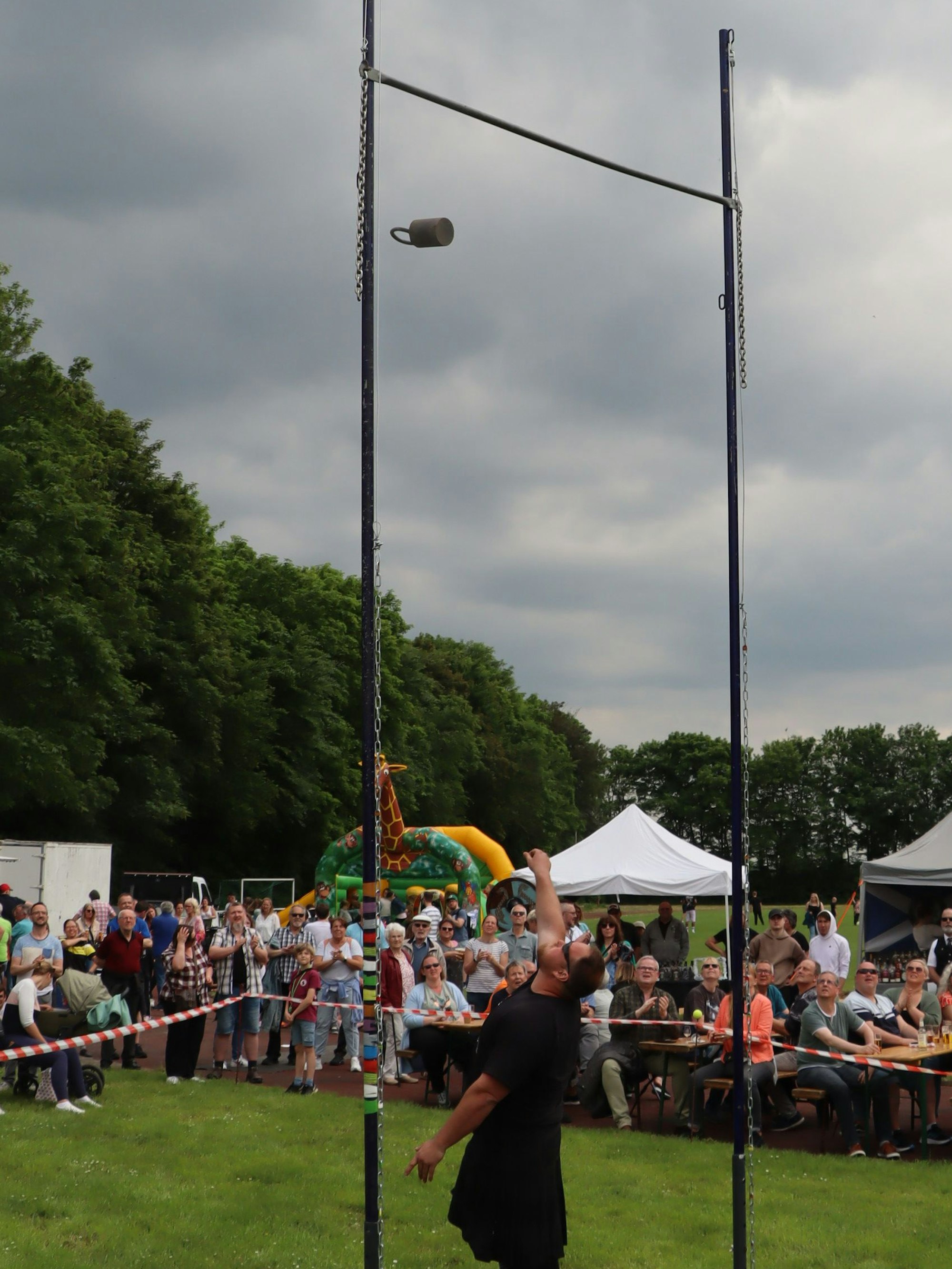 Das Bild zeigt einen Atlethen, der ein Gewicht über eine Stange wirft.