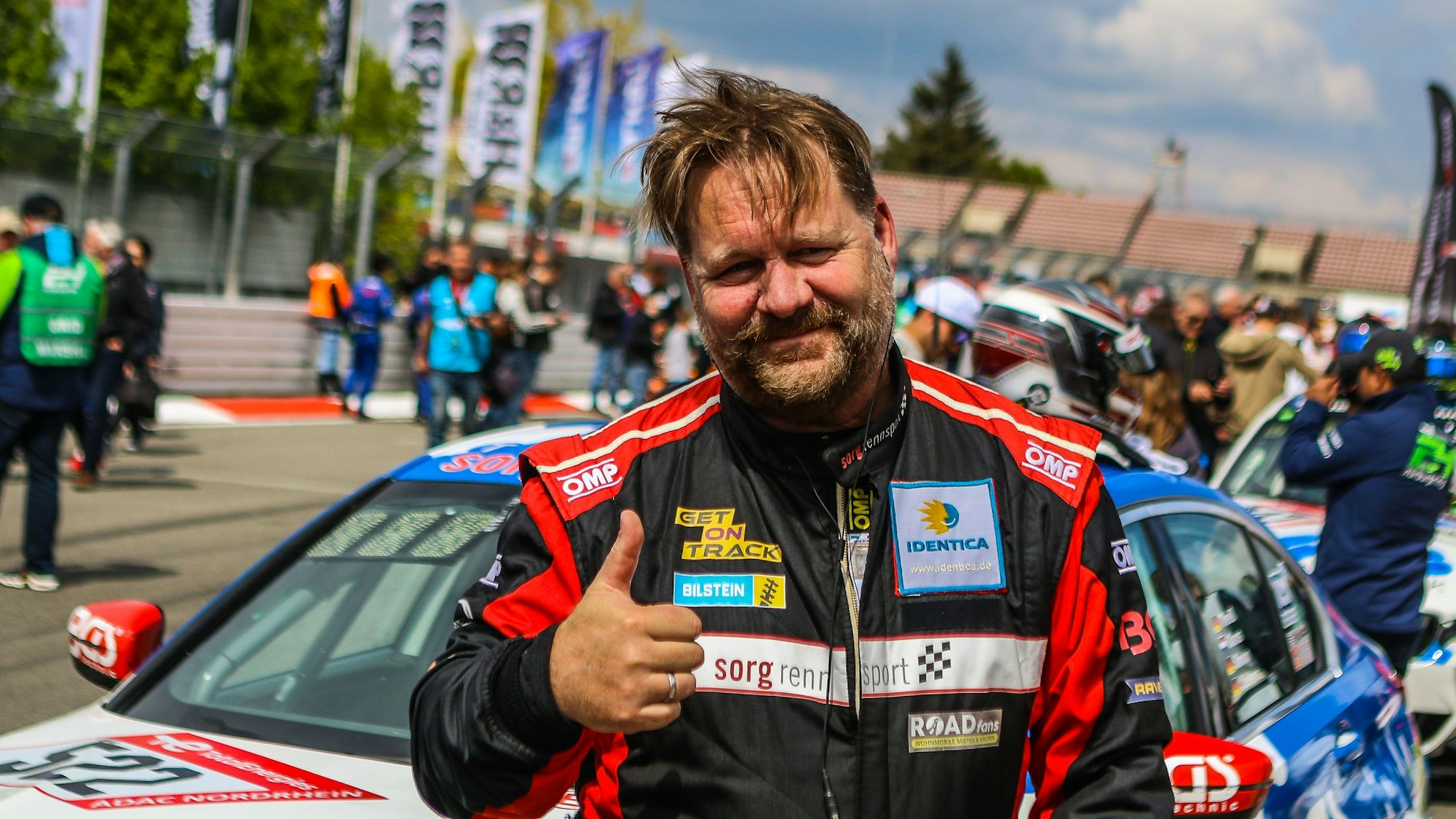 Björn Simon steht vor einem Fahrzeug und reckt den Daumen in die Höhe.