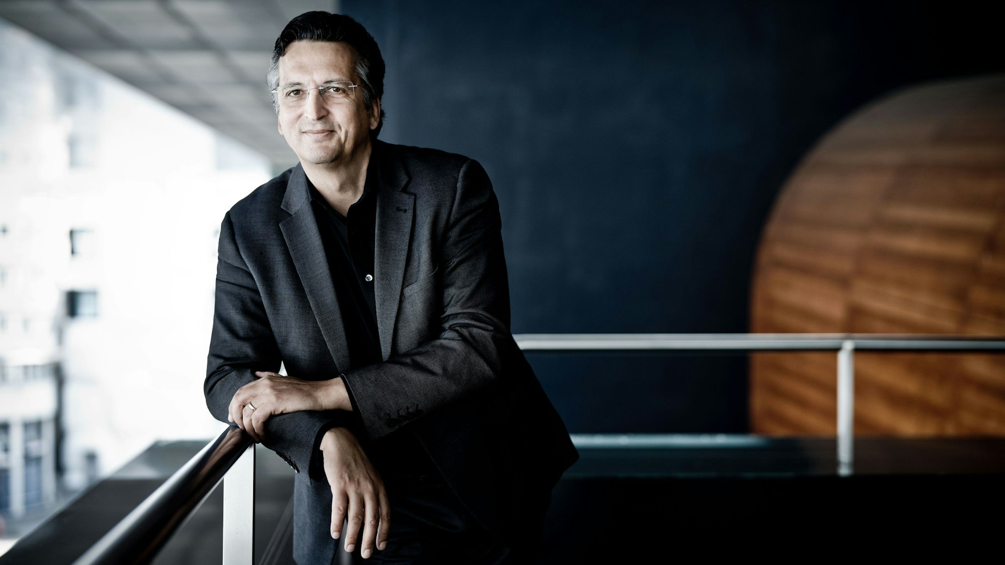 Michael Sanderling lehnt im Konzerhaus an einem Geländer.