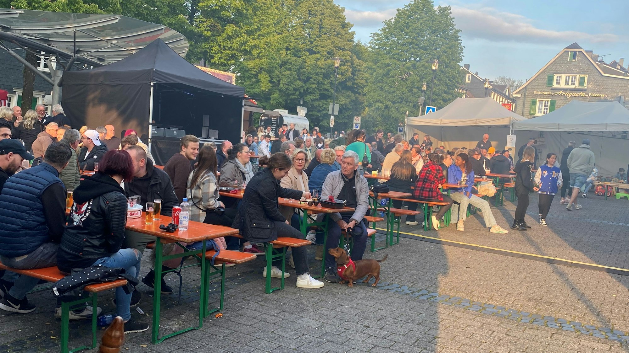 Gäste sitzen auf Bänken auf dem Altstadtfest in Burscheid.