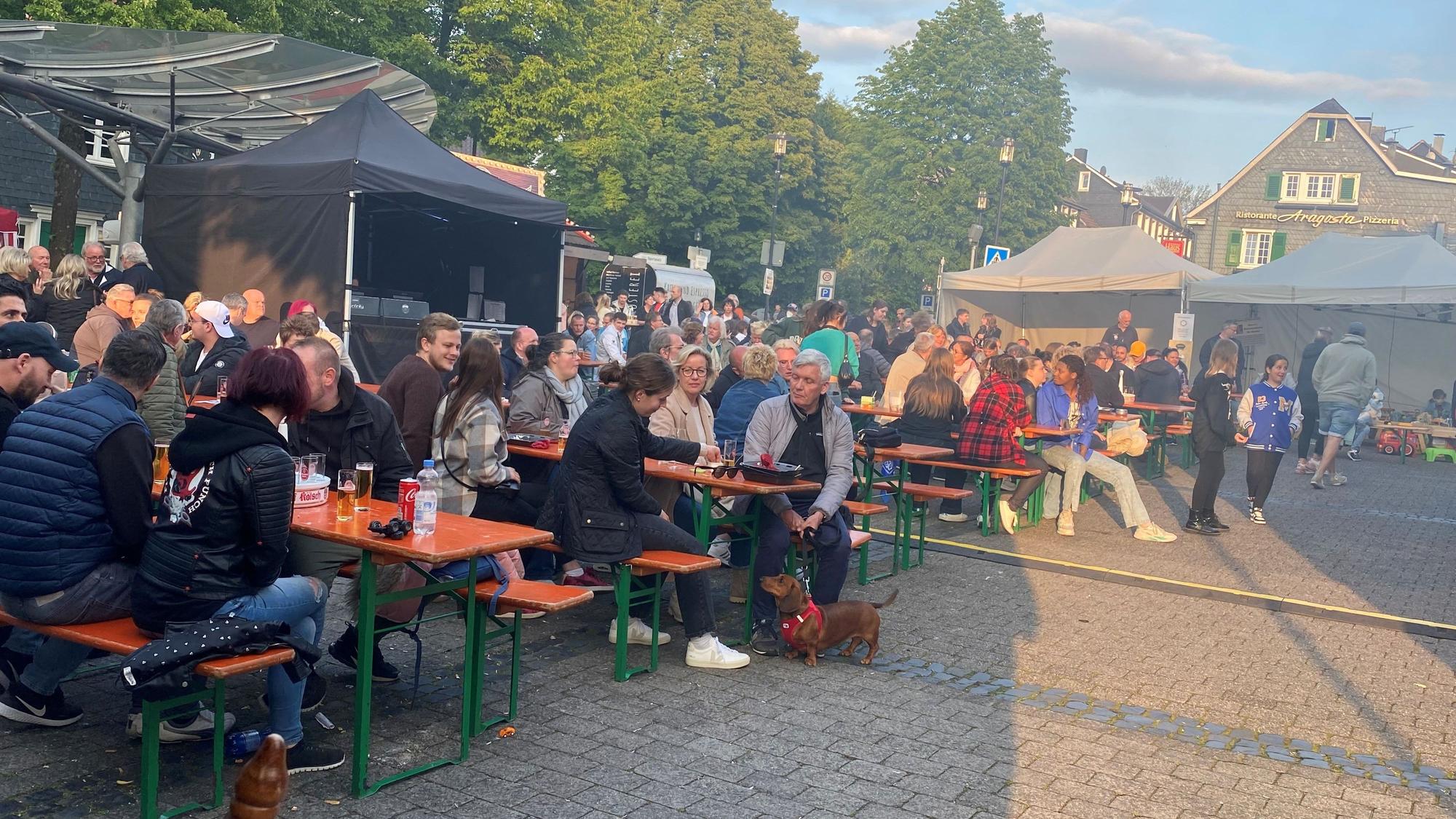 Gäste sitzen auf Bänken auf dem Altstadtfest in Burscheid.