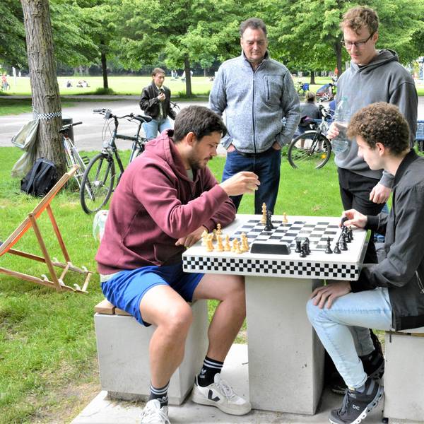 Zwei Männer sitzen im Inneren Grüngürtel vor einem Schachbrett.