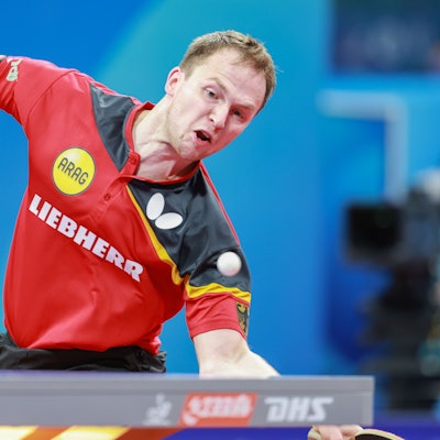 Im Bild ist ein Tischtennisspieler zu sehen, der gerade einen Ball annimmt.