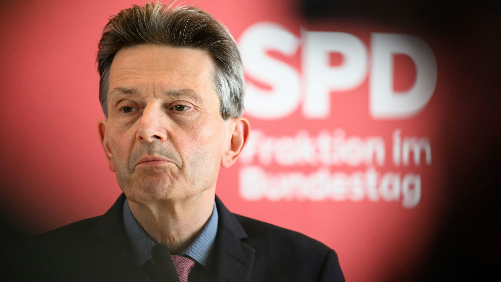 Es ist Rolf Mützenich zu sehen. Hinte ihm ist eine rote Wand mit der Aufschrift „SPD Fraktion im Bundestag“.
