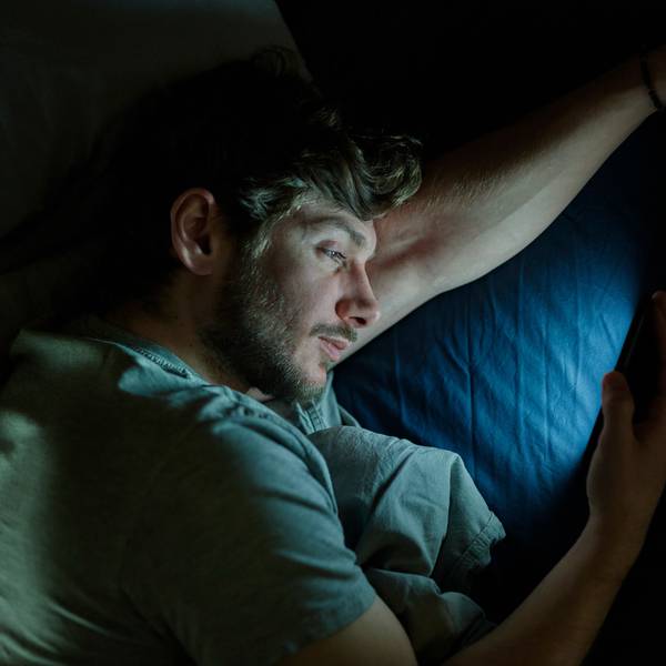 Ein Mann liest im Bett auf dem Smartphone