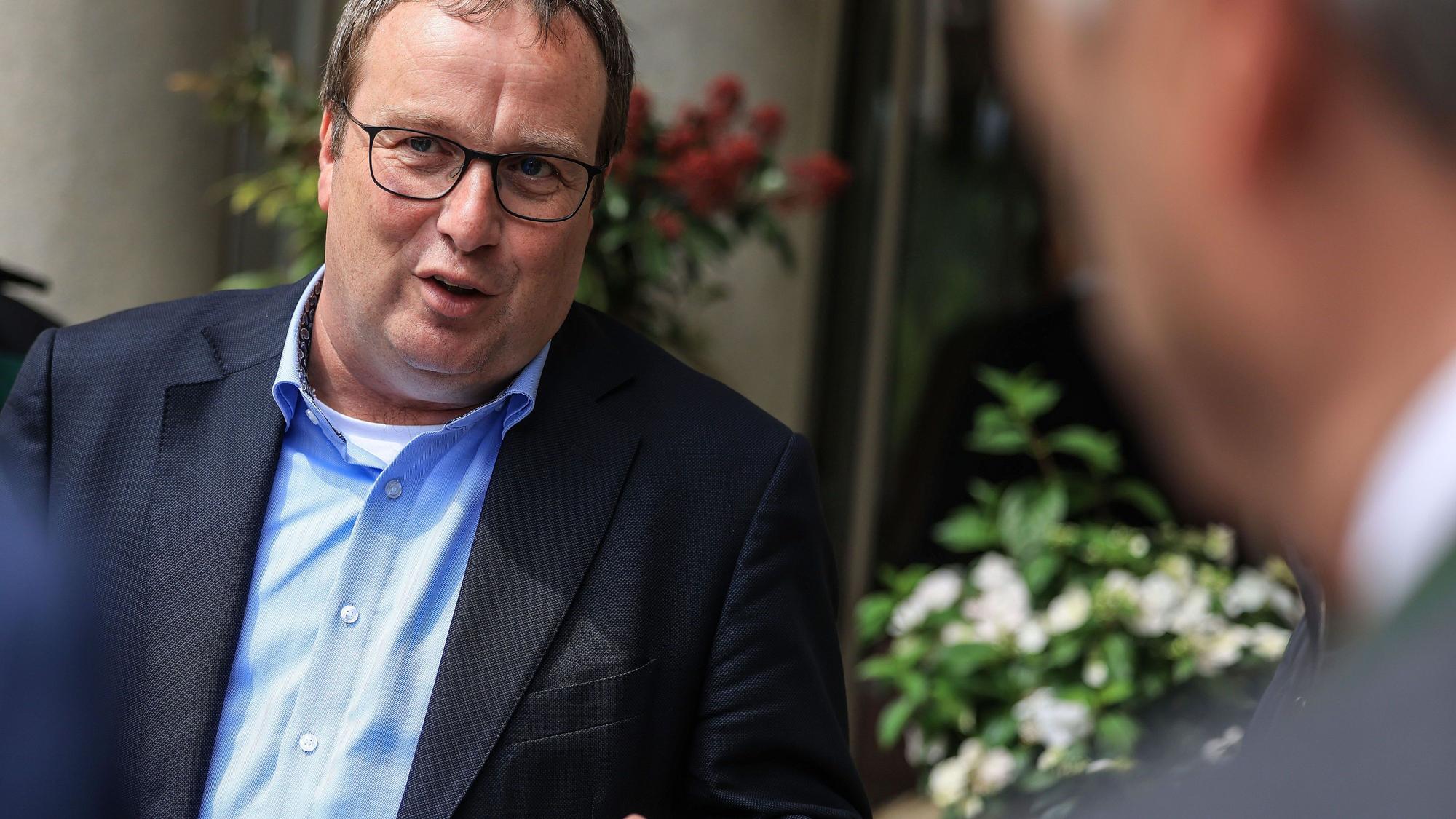 Oliver Krischer (Bündnis 90/Die Grünen), Minister für Umwelt, Naturschutz und Verkehr des Landes Nordrhein-Westfalen. Er trägt einen Anzug und ein blaues Hemd.
