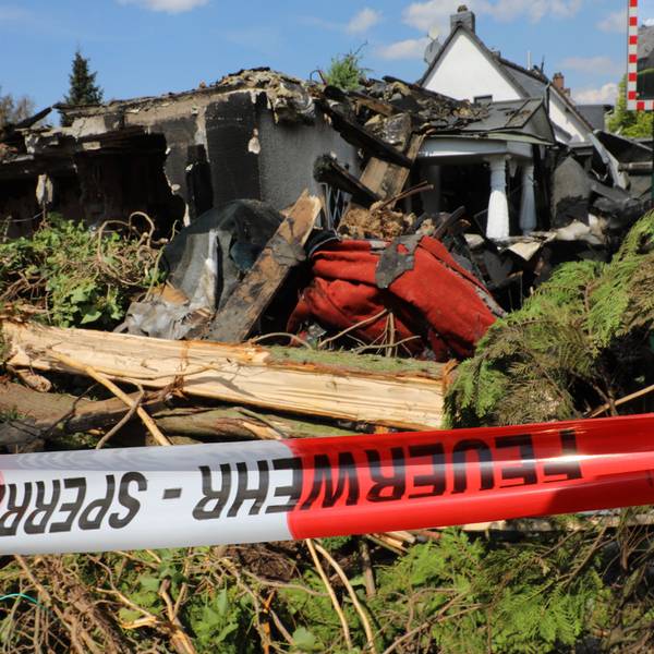 Vor dem abgebrannten Haus hängt ein Absperrband.