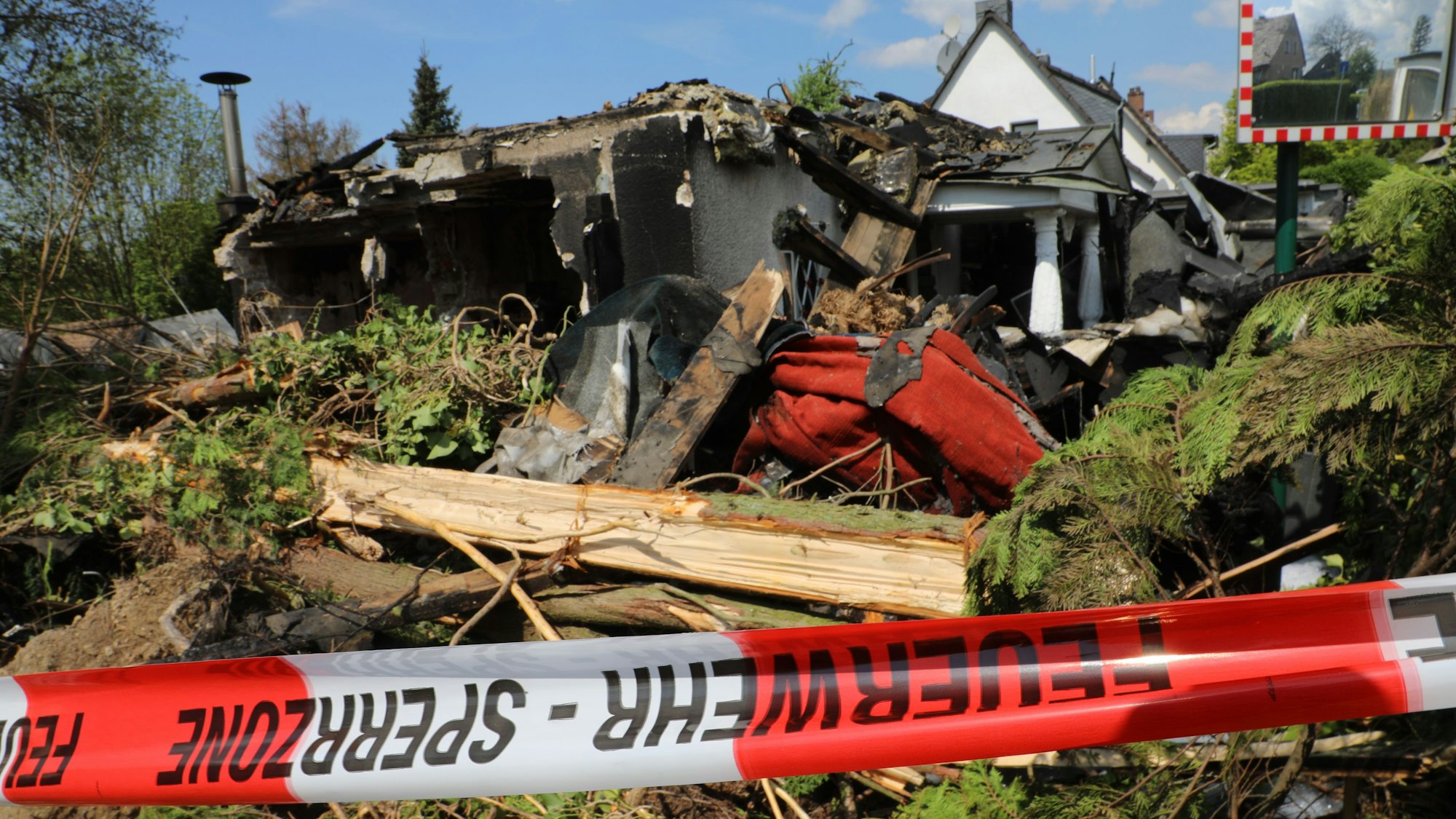 Vor dem abgebrannten Haus hängt ein Absperrband.