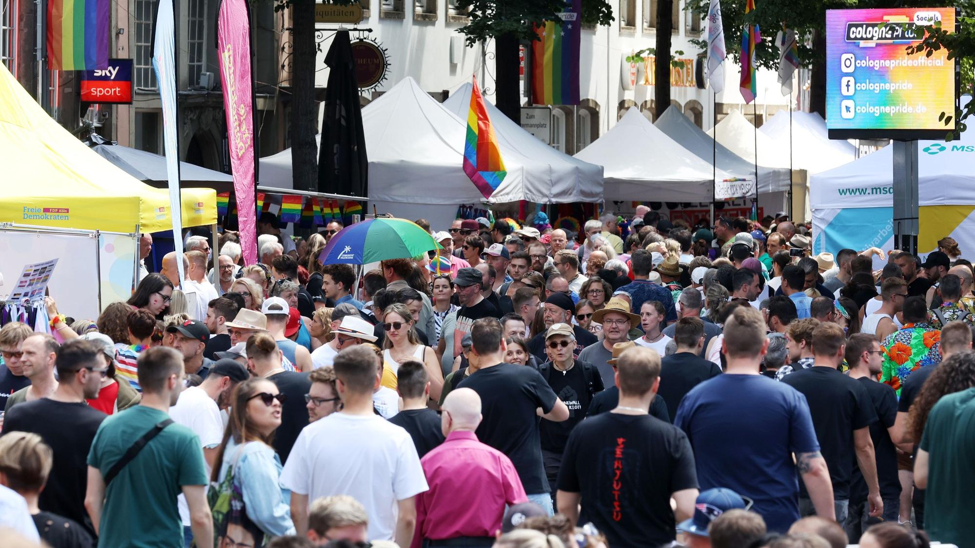 Menschengruppen laufen an Pavillionzelten vorbei während des CSD-Straßenfest ses im Sommer 2022 in der Kölner Altstadt.