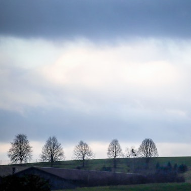 Hinter einem Windrad ziehen Regenwolken auf.
