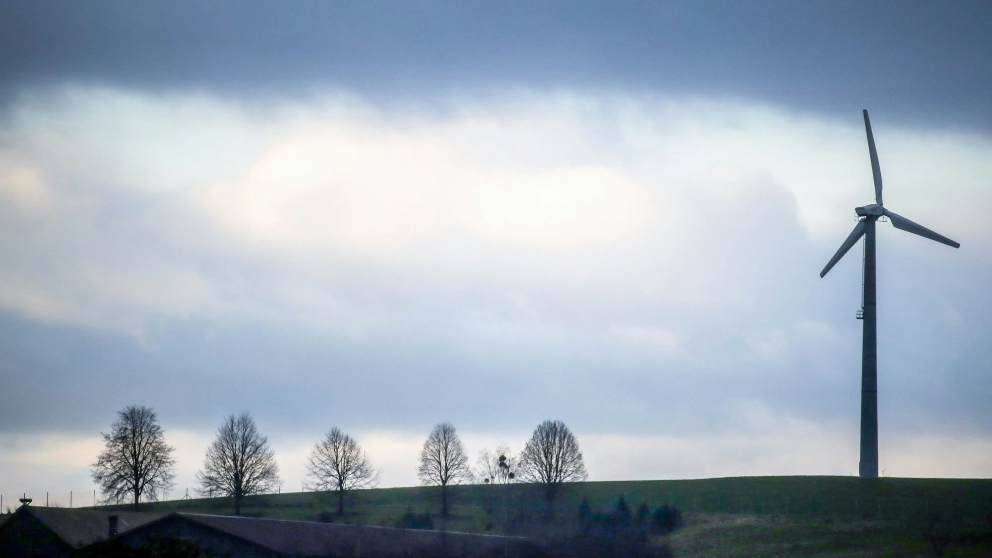 Hinter einem Windrad ziehen Regenwolken auf.