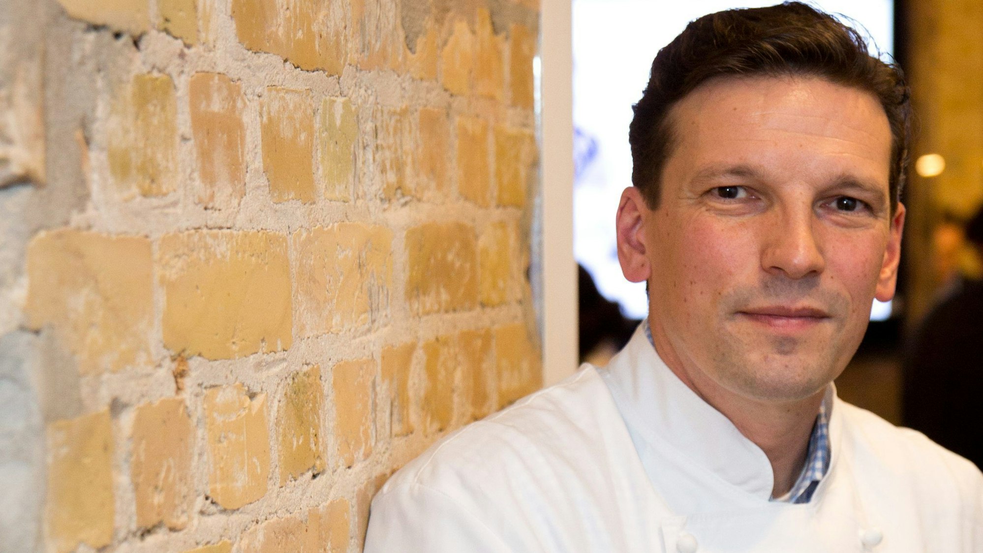 Der Sternekoch Christian Jürgens posiert vor einer Mauer