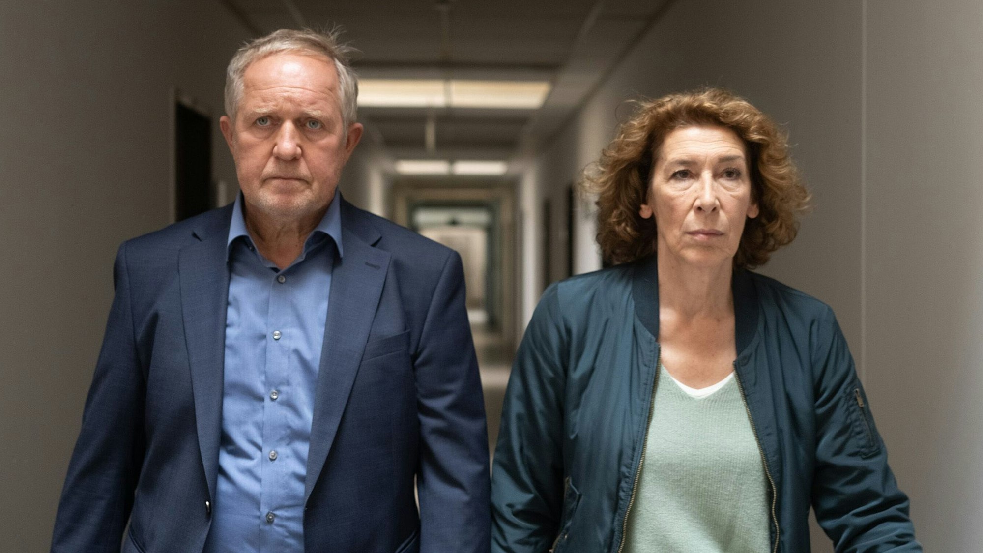 Die beiden Ermittler gehen durch einen Bürogang in Richtung der Kamera. Sie schauen ernst, Moritz Eisner wirkt bedrückt.
