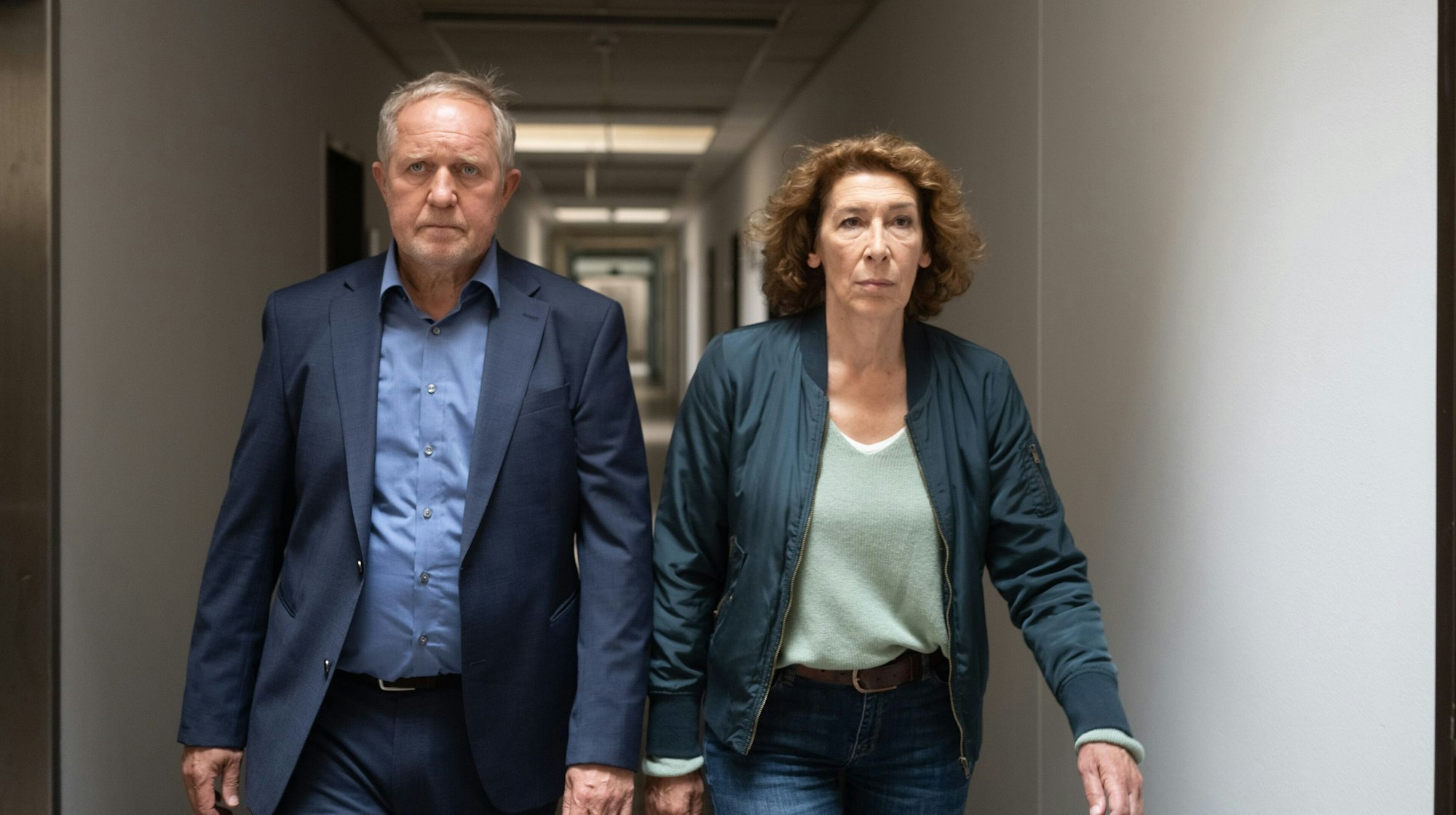 Die beiden Ermittler gehen durch einen Bürogang in Richtung der Kamera. Sie schauen ernst, Moritz Eisner wirkt bedrückt.