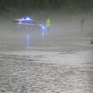 Schwere Unwetter in Detmold (Ostwestfalen-Lippe): Ein Polizist und ein Autofahrer stehen an einer überfluteten Straße nach dem Starkregen am Montagabend.