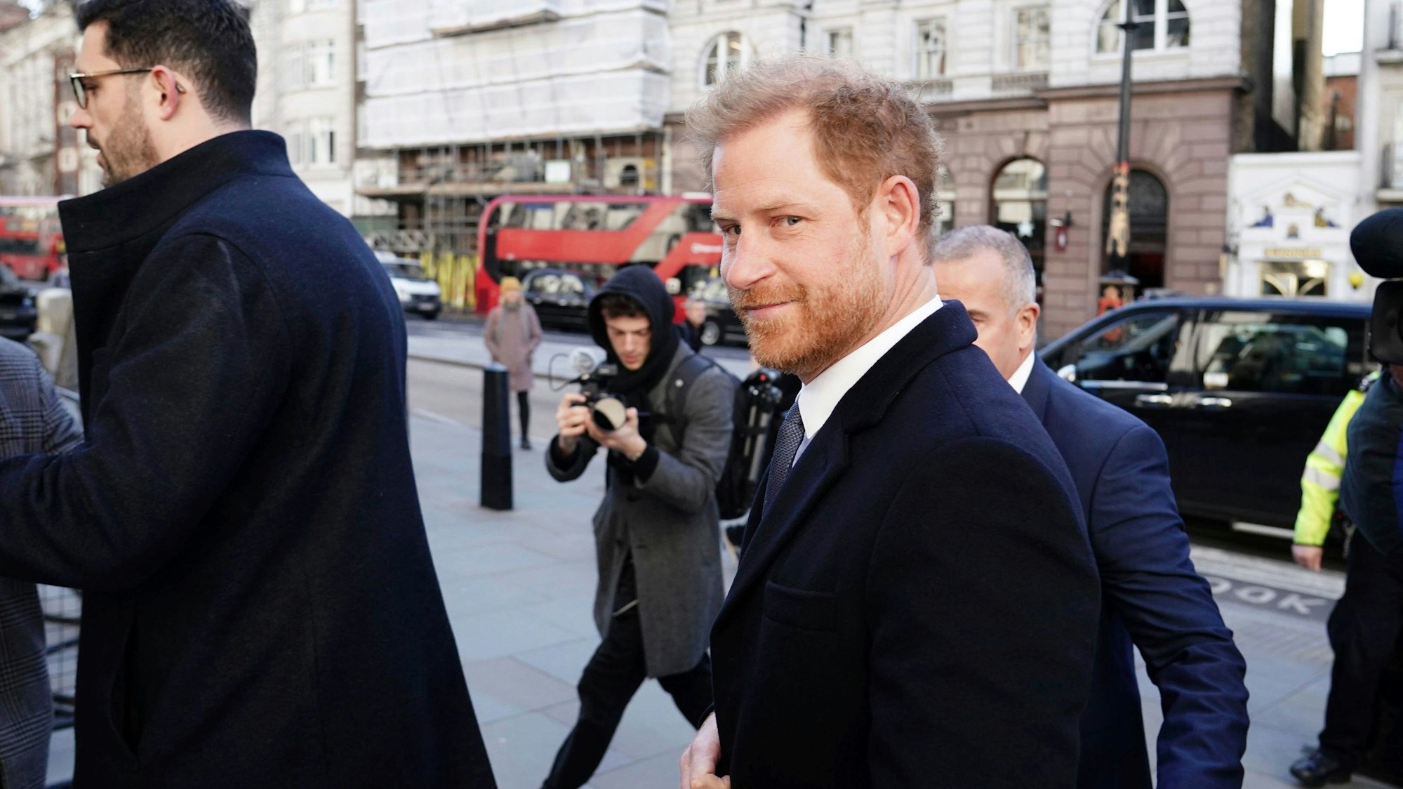 Prinz Harry kommt bei den Royal Courts Of Justice in London an. Hinter und neben ihm sind Paparazzis und Anwälte.