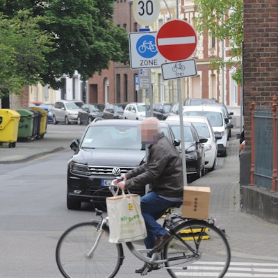 Die Fahrradzone in der Frechener Innenstadt. Ein Mann fährt auf einem Fahrrad über die Straße. Im Hintergrund markiert ein Schild die Fahrradzone.