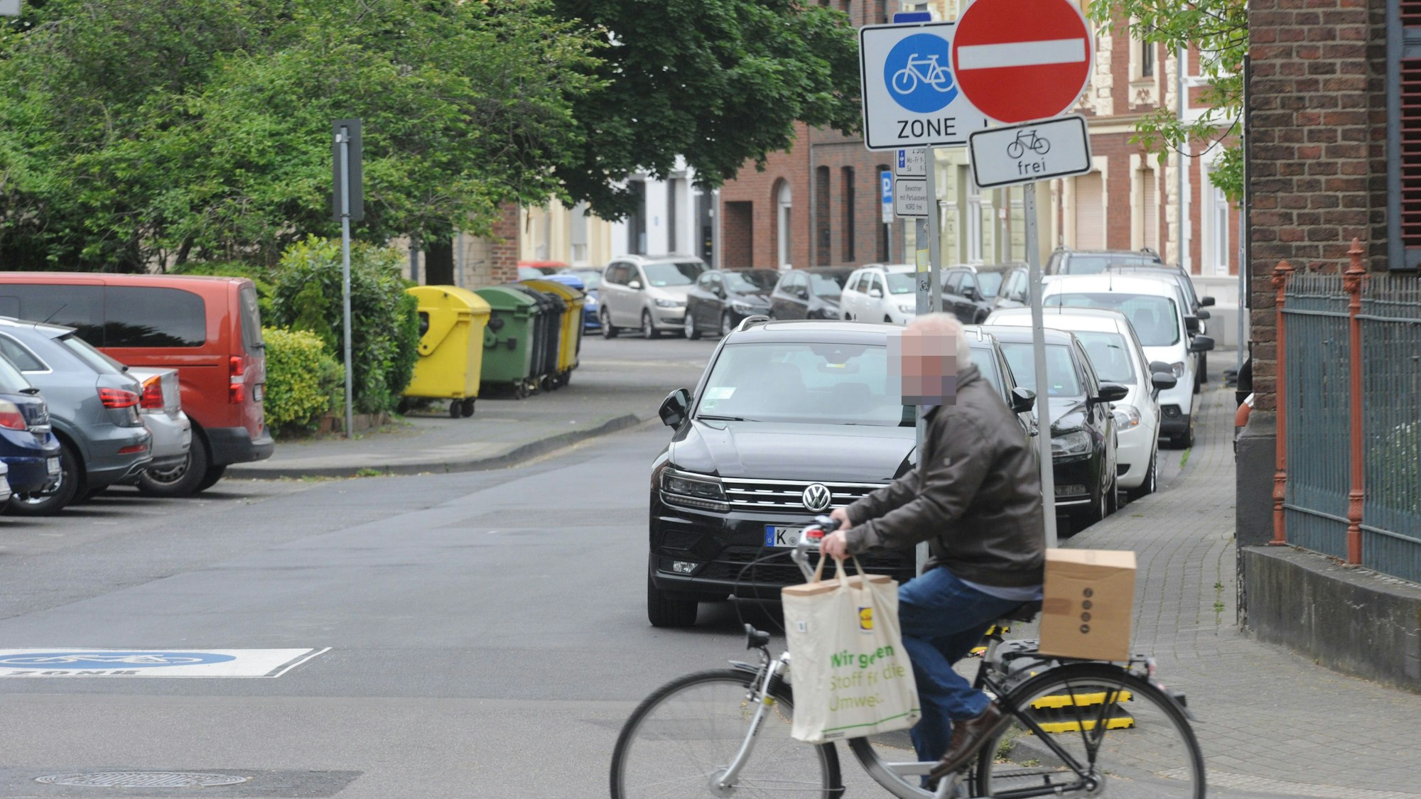Die Fahrradzone in der Frechener Innenstadt. Ein Mann fährt auf einem Fahrrad über die Straße. Im Hintergrund markiert ein Schild die Fahrradzone.