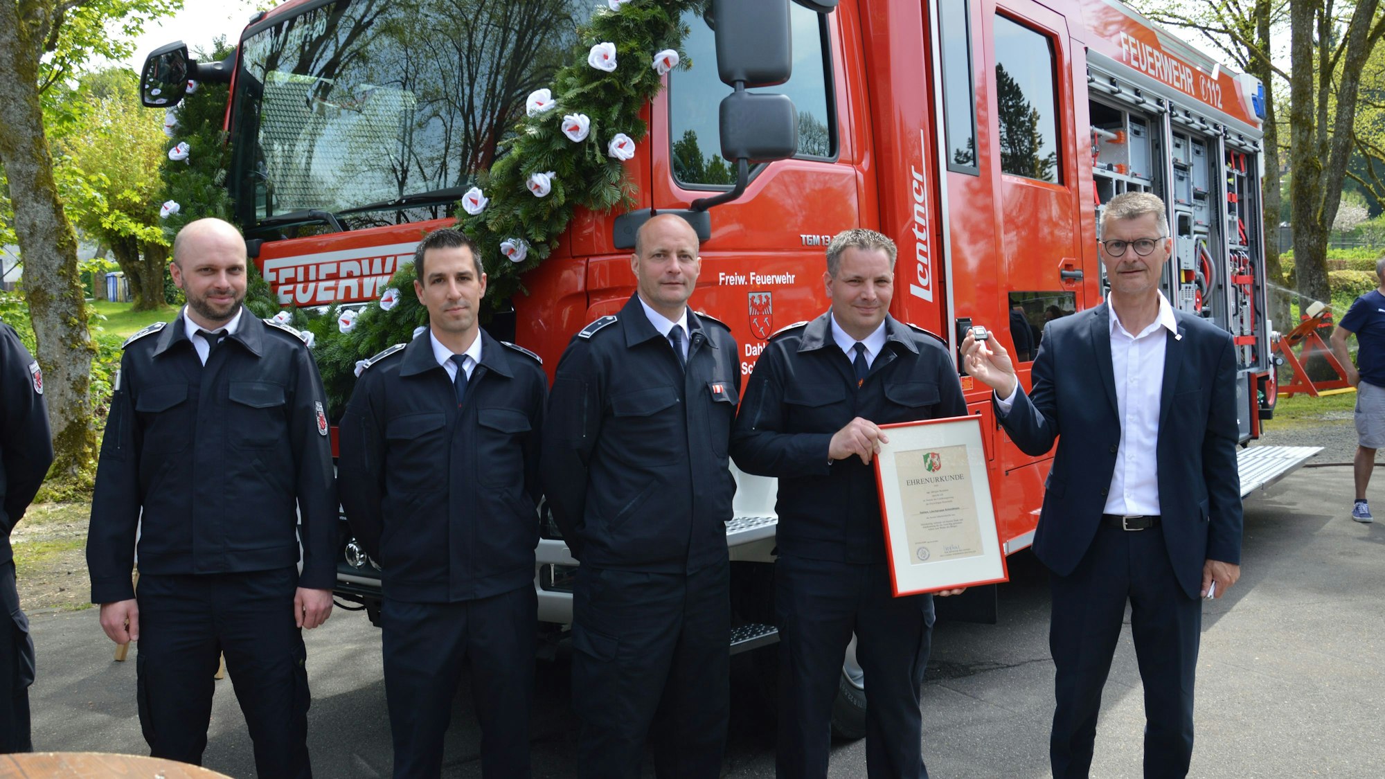 Es sind die fünf Männer vor dem Feuerwehrfahrzeug zu sehen.