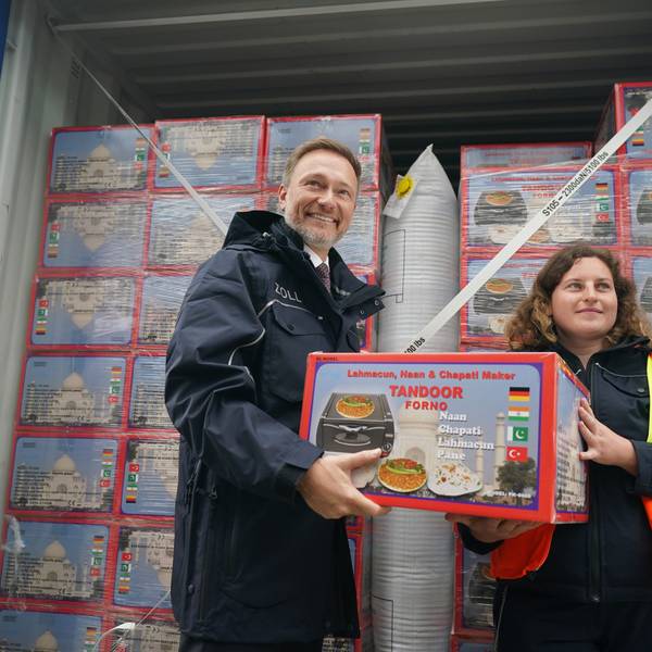 Christian Lindner (FDP, l), Bundesminister der Finanzen, und Katharina Lorenzen, Zollinspektorin, tragen einen Karton mit einem elektrischen Tischofen von einem Lkw-Container zu einem mobilen Röntgengerät während Lindners Besuch in der Zollabfertigung im Zollamt Hamburg.
