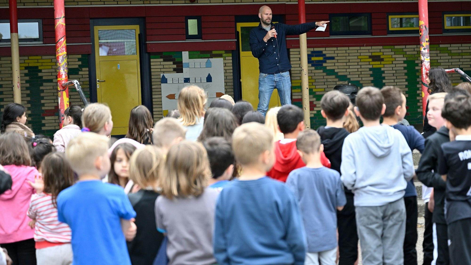 Der stellvertretende Schulleiter Christian Brachten steht vor den Grundschülern und kündigt eine Überraschung an.