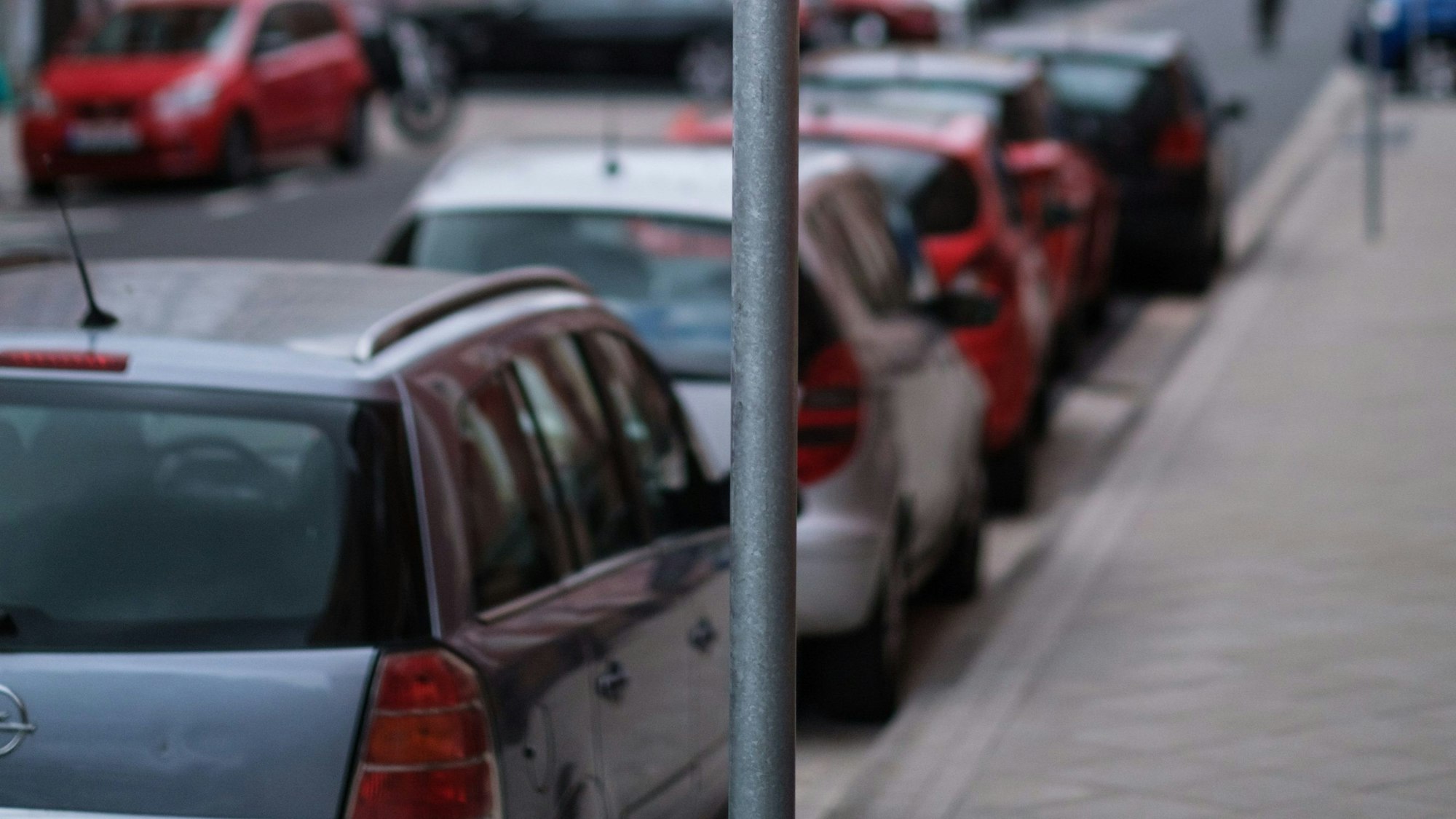 Es sind mehrere parkende Autos an der Straßenseite zu sehen.