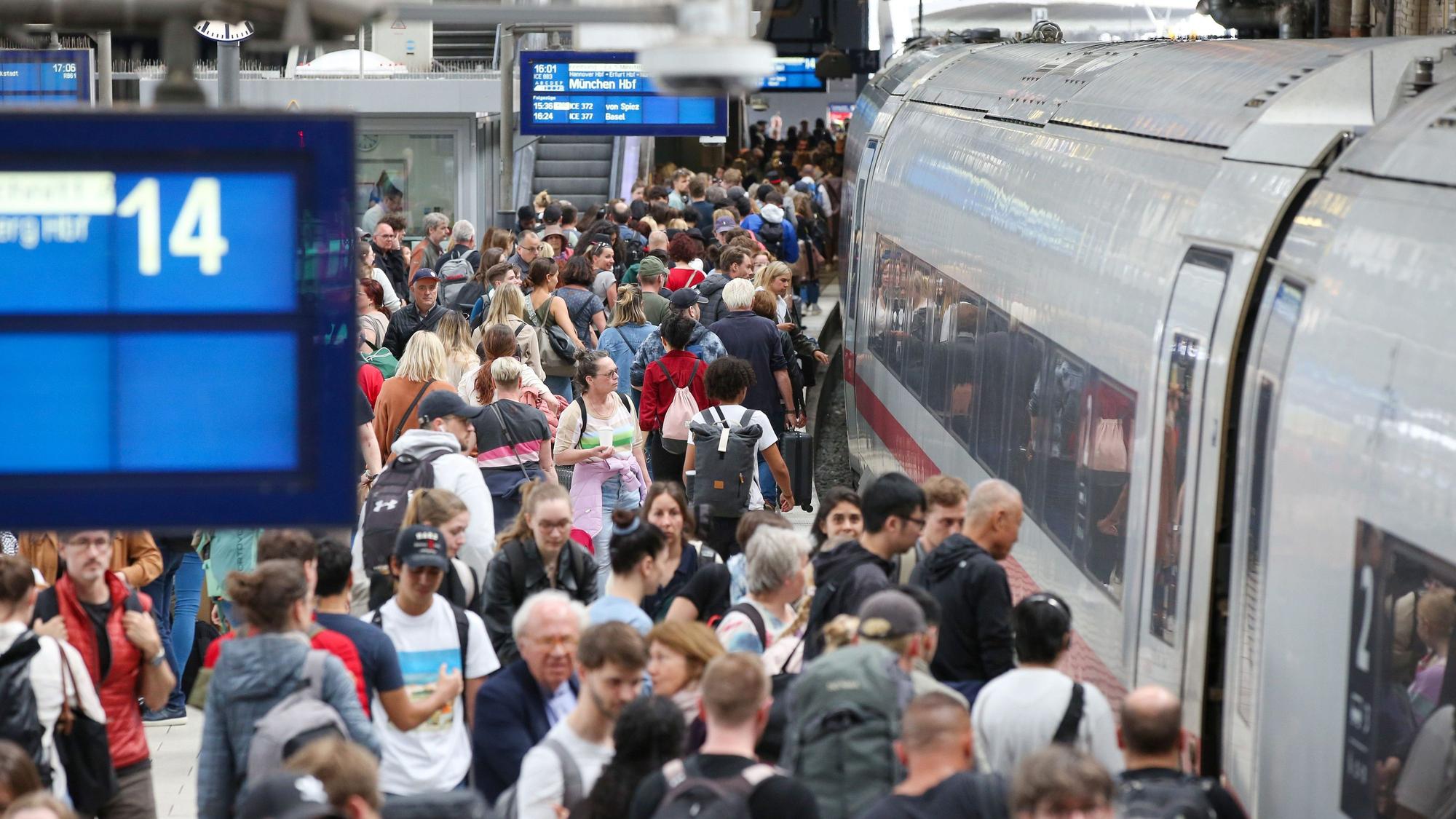 Zahlreiche Reisende sind auf einem vollen Bahnsteig unterwegs.
