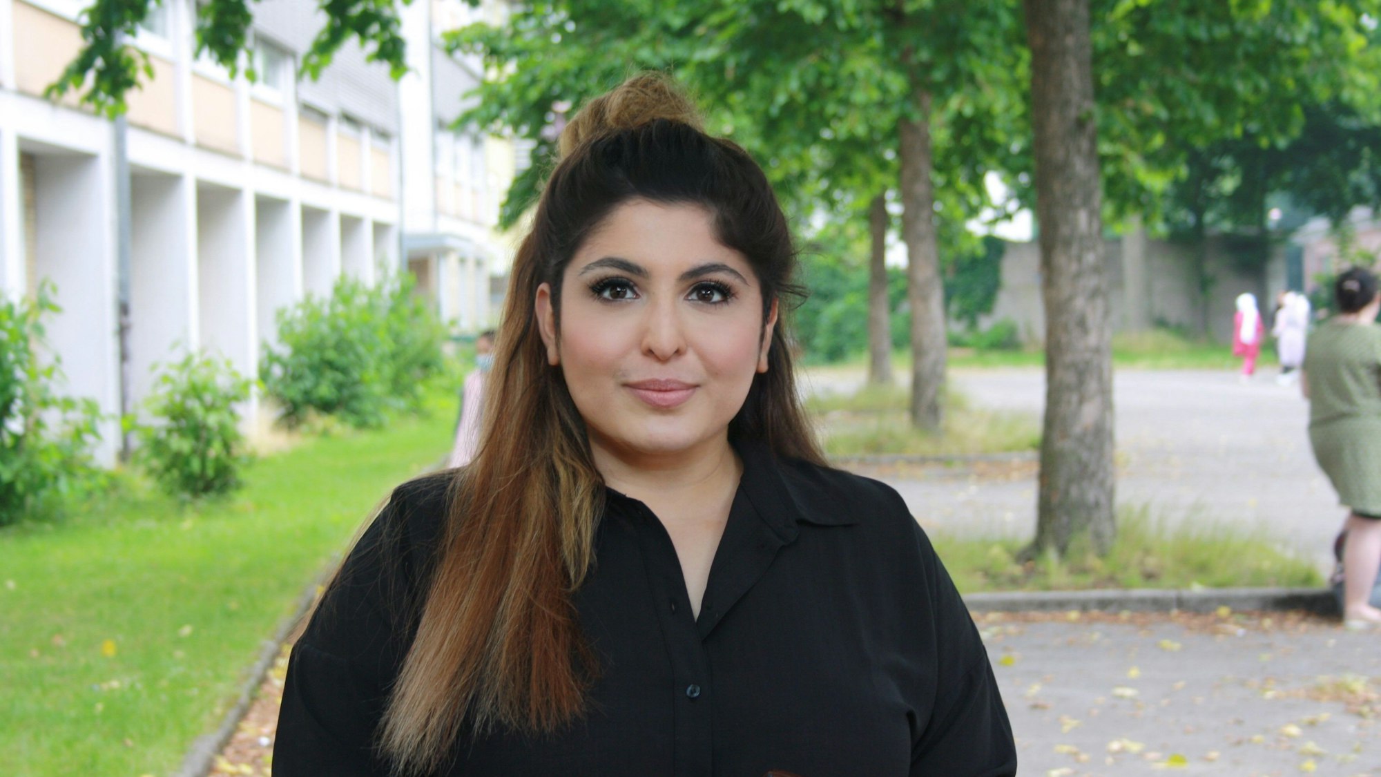 Die Kölner Lehrerin Bahar Aslan steht in einem Innenhof und blickt in die Kamera.