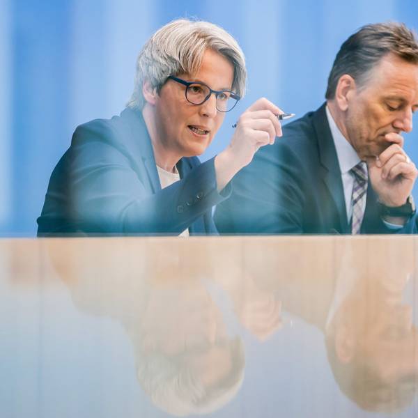 Eine Frau mit Brille und ein Mann werden auf einem Pult gespiegelt.
