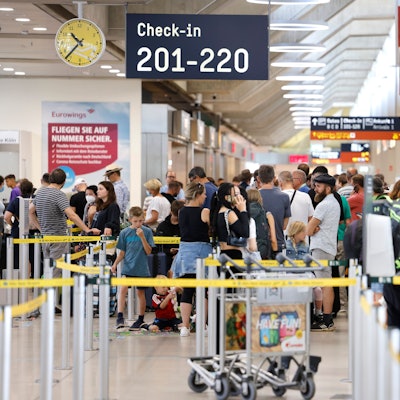 Passagiere stehen am Samstag-Vormittag in einer Schlange von mehreren hundert Metern für die Sicherheitskontrolle am Flughafen Köln Bonn an.