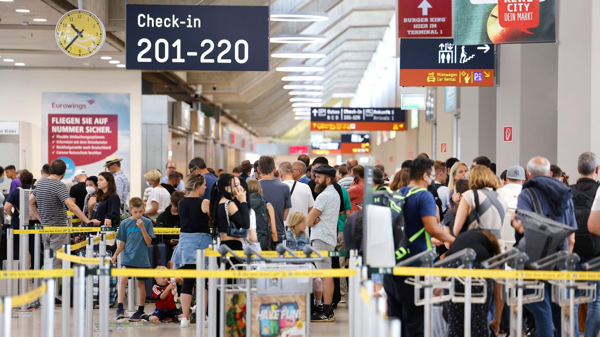 Passagiere stehen am Samstag-Vormittag in einer Schlange von mehreren hundert Metern für die Sicherheitskontrolle am Flughafen Köln Bonn an.