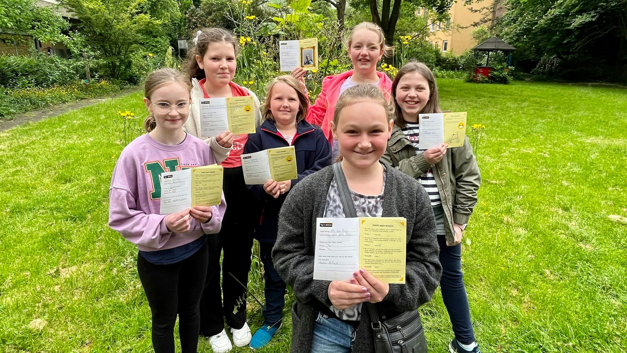 Sechs Mädchen mit Ausweisen im Schulgarten
