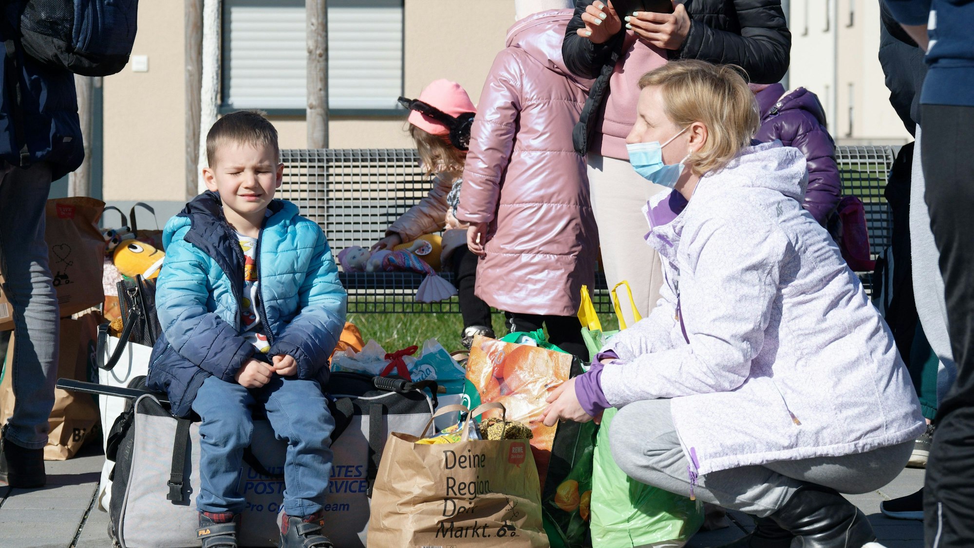 03.03.2022, Nordrhein-Westfalen, Köln: Geflüchtete aus der Ukraine stehen mit ihrem Gepäck vor den Gebäuden eines Flüchtlingsheims in Köln Worringen. Foto: Henning Kaiser/dpa +++ dpa-Bildfunk +++