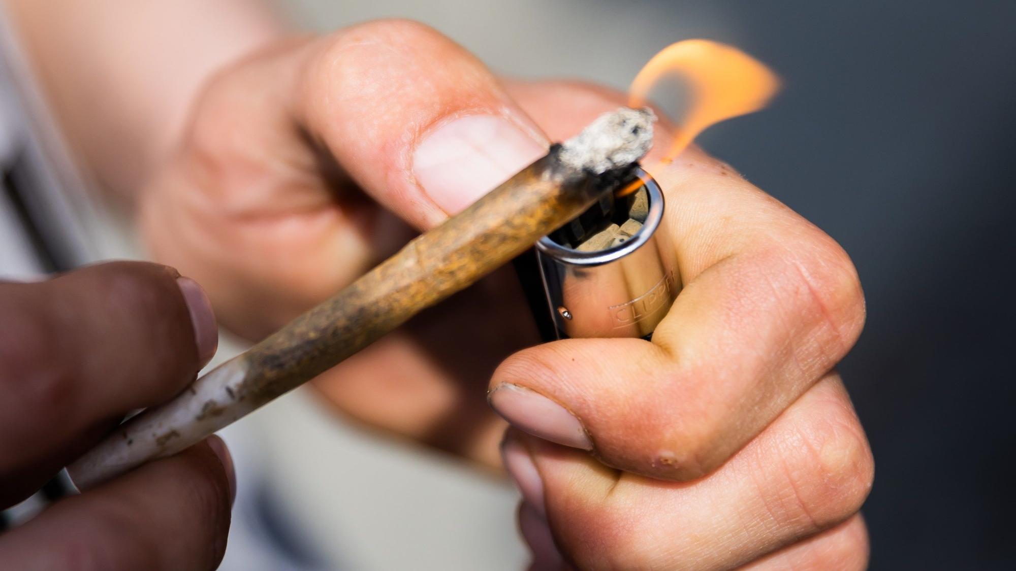 Ein Mann zündet bei der Auftaktkundgebung einer Demonstration für eine zügige Legalisierung von Cannabis, dem «Global Marijuana March 2022», am Brandenburger Tor einen Joint mit Medizinalcannabis an. Ab Donnerstag 25. Mai gilt im alten Zentrum der niederländischen Hauptstadt ein Kiff-Verbot. Es ist eine neue Maßnahme gegen Probleme durch Über-Tourismus