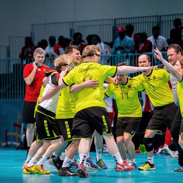 Mehrere Sportler jubeln in einer Sporthalle.