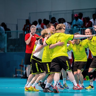 Mehrere Sportler jubeln in einer Sporthalle.