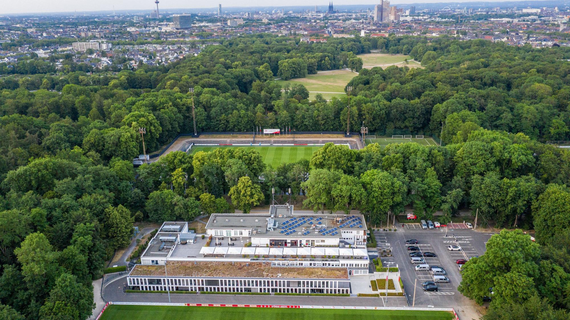 Das Geißbockheim genannte Clubhaus des Fußballverein 1. FC Köln mit dem Trainingsplatz 1 (vorne) und dem Franz-Kremer-Stadion (hinten) im Äußeren Grüngürtel. Im Hintergrund sind das Stadtzentrum und der Beethovenpark zu erkennen.