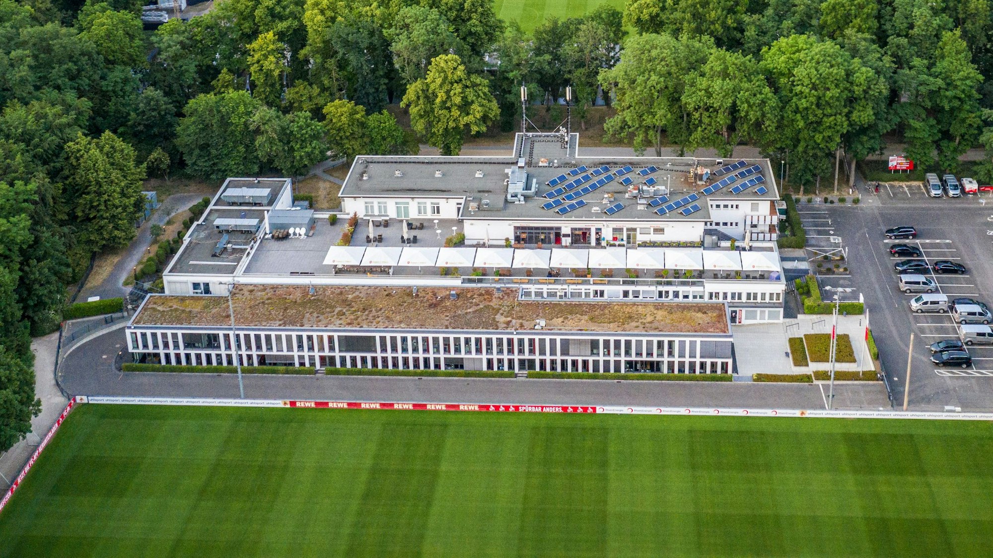 Das Geißbockheim genannte Clubhaus des Fußballverein 1. FC Köln mit dem Trainingsplatz 1 (vorne) und dem Franz-Kremer-Stadion (hinten) im Äußeren Grüngürtel. Im Hintergrund sind das Stadtzentrum und der Beethovenpark zu erkennen.