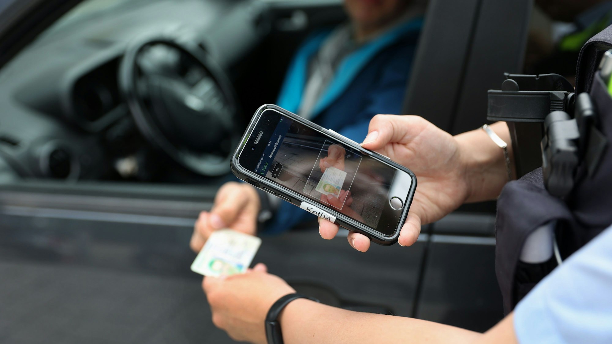 Eine Polizistin hält ein Handy über einen Personalausweis, um Daten zu einer Person abzufragen.