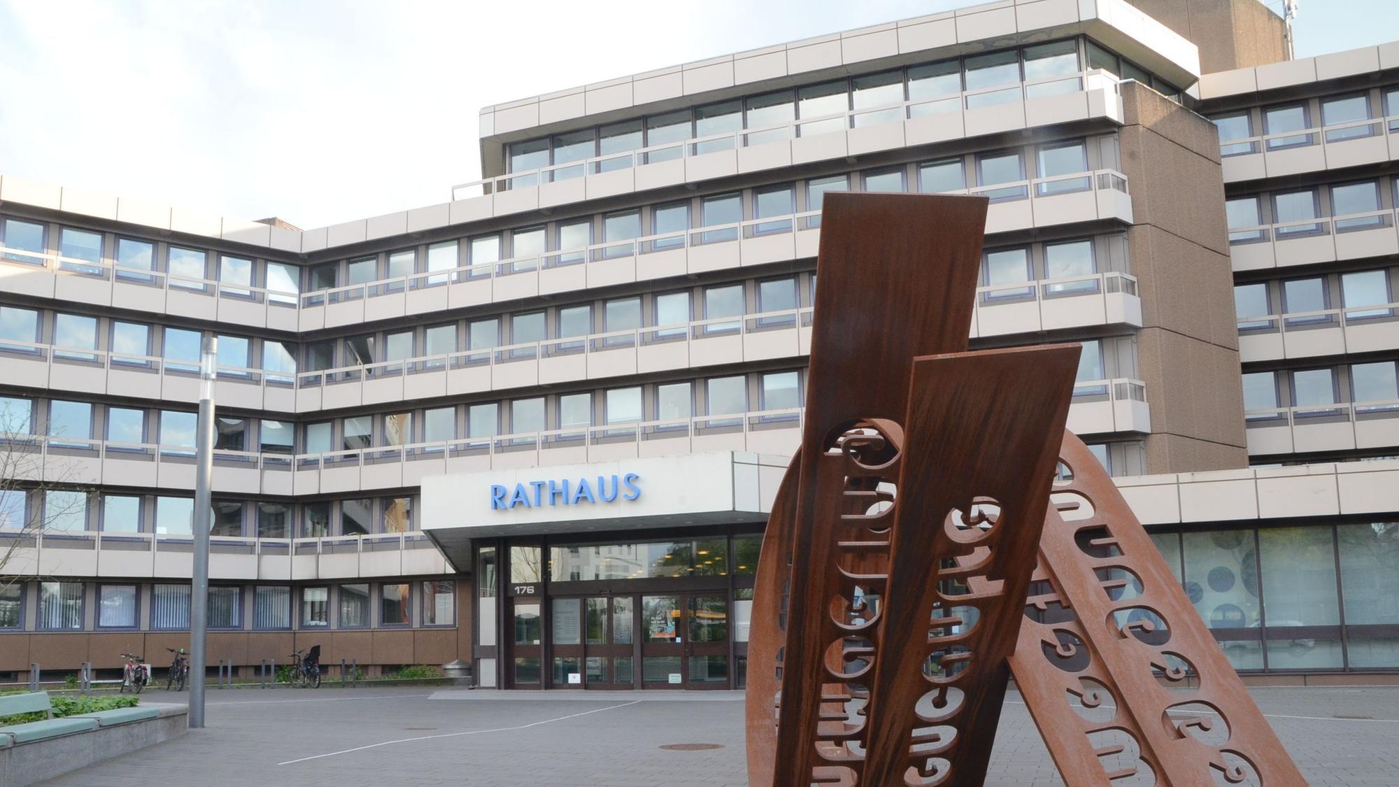 Das Foto zeigt die Front des Troisdorfer Rathauses und ein Kunstinstallation auf dem Platz davor.