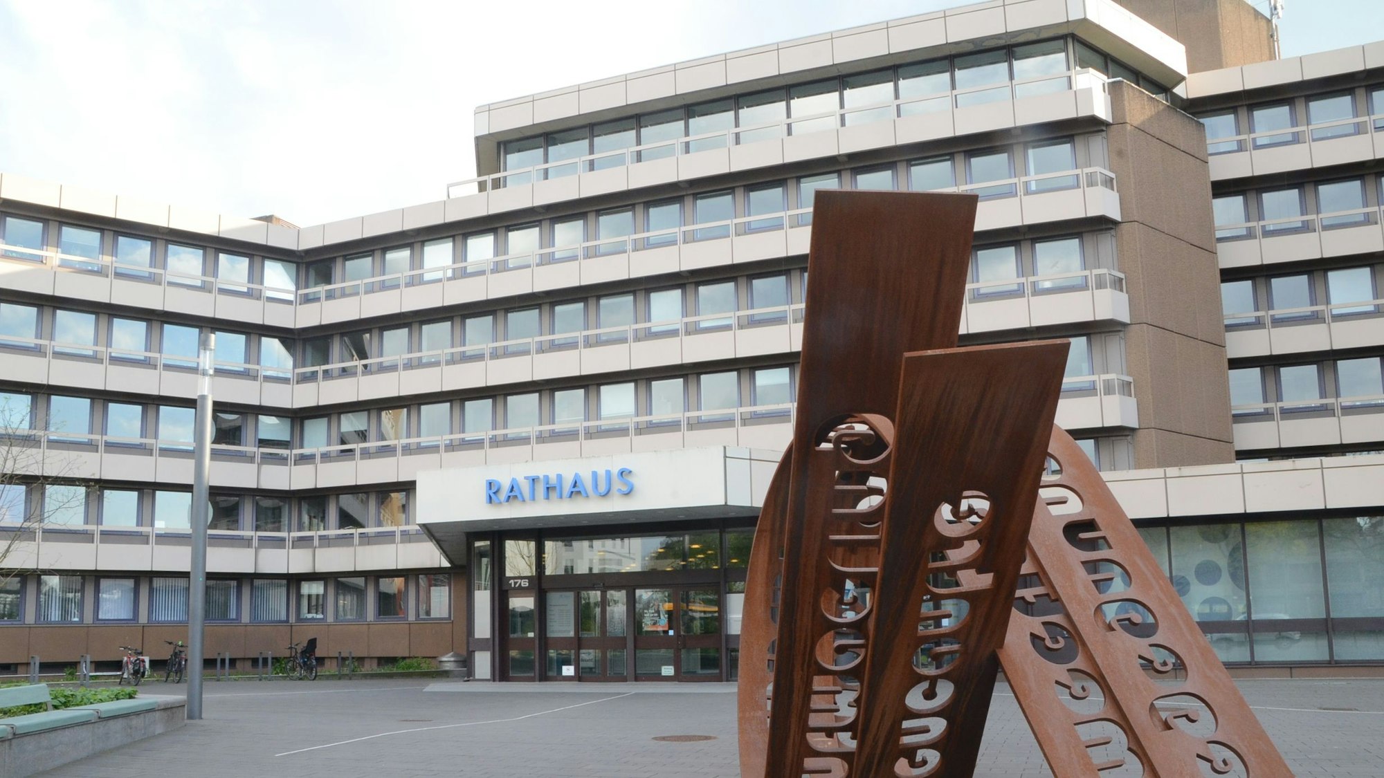 Das Foto zeigt die Front des Troisdorfer Rathauses und ein Kunstinstallation auf dem Platz davor.