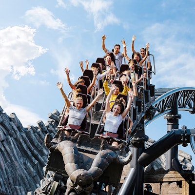 Menschen in einer Achterbahn reißen ihre Arme nach oben.